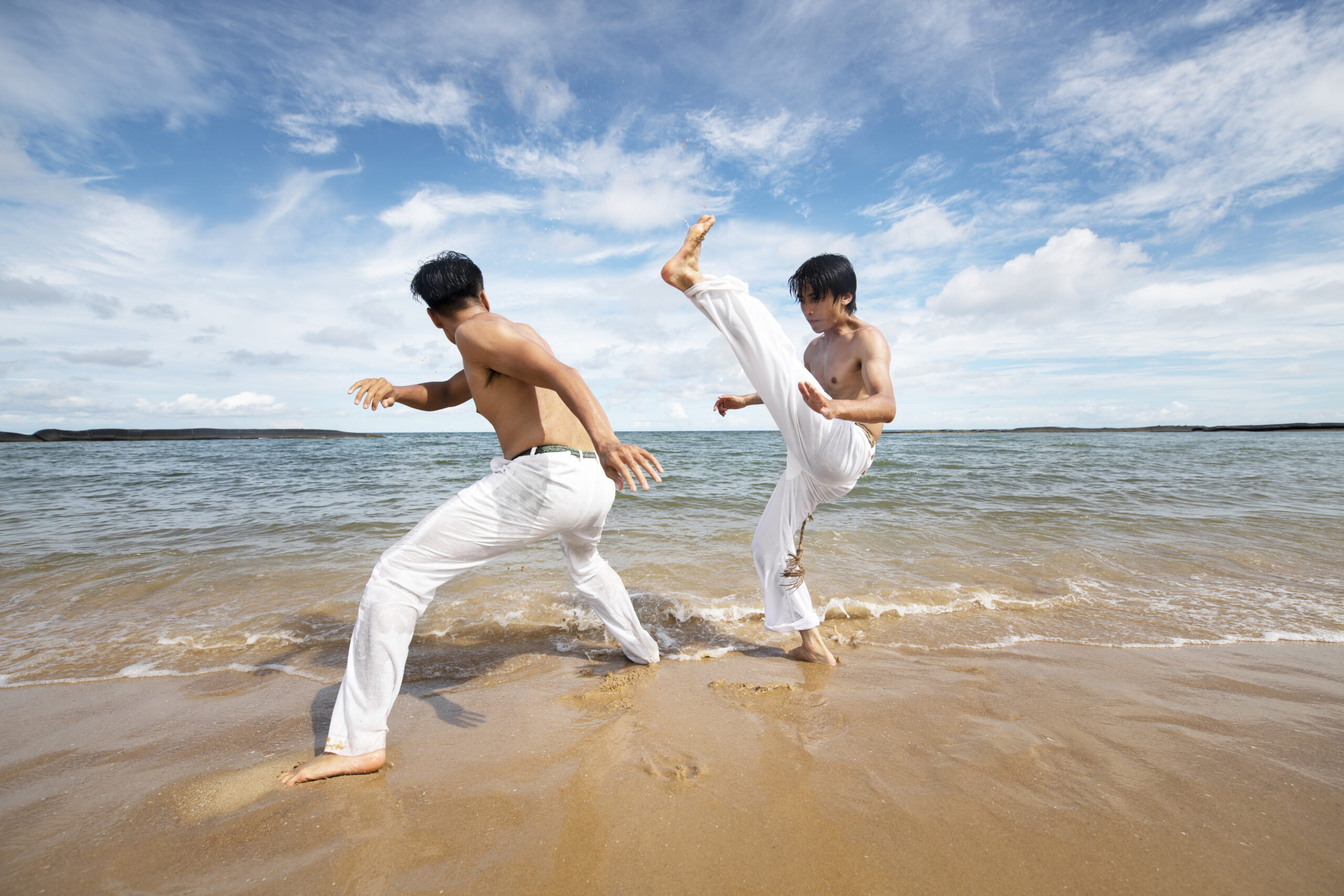 men-by-beach-practicing-capoeira-together